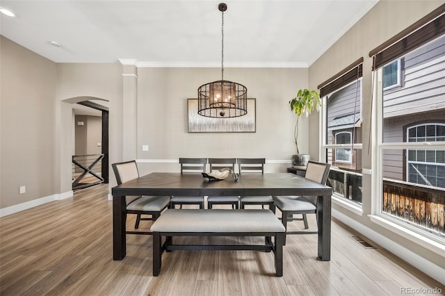10553 Stonemeadow Dr, Parker, CO 80134 - dining area featuring arched walkways, light wood-style floors, a chandelier, and crown molding