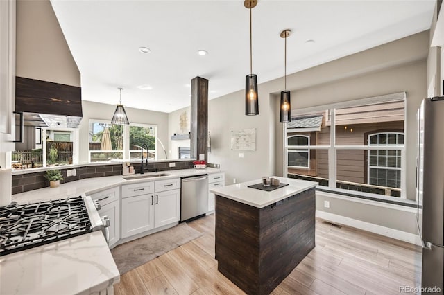 10553 Stonemeadow Dr, Parker, CO 80134 - kitchen with appliances with stainless steel finishes, light wood-style flooring, light stone countertops, a center island, and tasteful backsplash