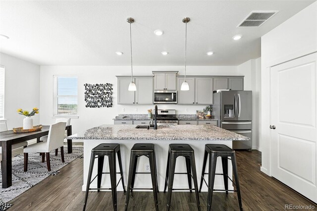 226 Racer St, Bennett, CO 80102 - kitchen featuring stainless steel appliances, gray cabinetry, a kitchen breakfast bar, a center island with sink, and recessed lighting
