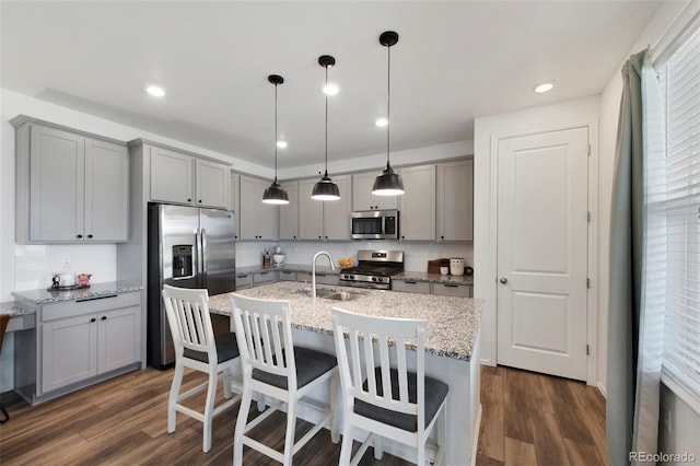 12826 Lake Port St, Longmont, CO 80504 - kitchen with stainless steel appliances, gray cabinetry, dark wood finished floors, a center island with sink, and recessed lighting
