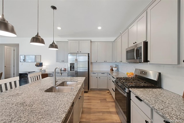 12826 Lake Port St, Longmont, CO 80504 - kitchen with appliances with stainless steel finishes, light wood finished floors, decorative light fixtures, recessed lighting, and light stone countertops