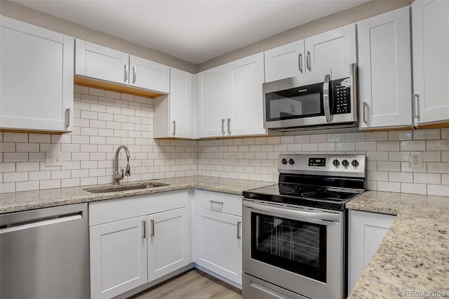 kitchen with decorative backsplash, white cabinetry, sink, and stainless steel appliances