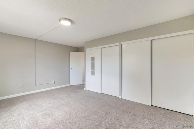 unfurnished bedroom featuring multiple closets and carpet floors