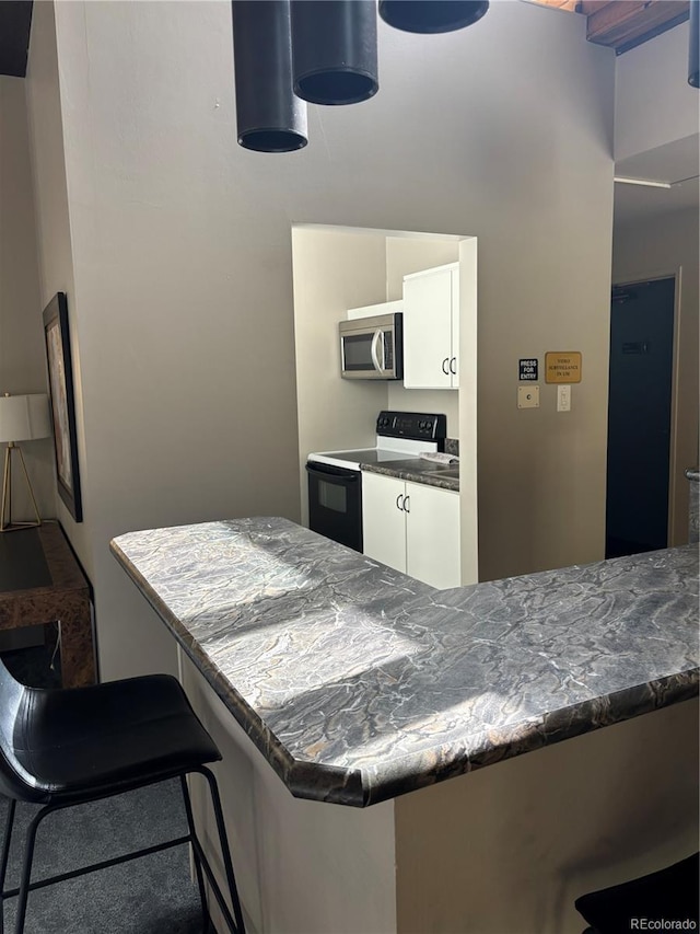 kitchen featuring kitchen peninsula, white cabinetry, black range with electric stovetop, and a breakfast bar