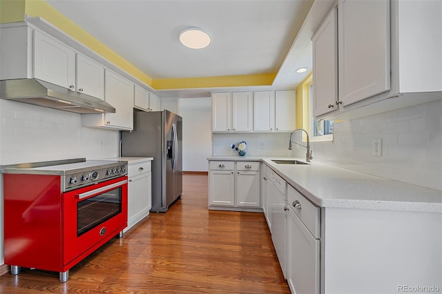 kitchen featuring tasteful backsplash, stainless steel appliances, sink, hardwood / wood-style floors, and white cabinetry