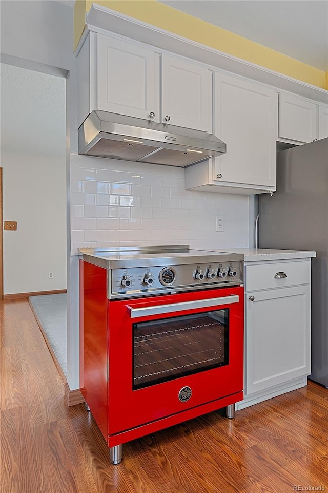 kitchen with decorative backsplash, white cabinetry, stainless steel appliances, and light hardwood / wood-style floors