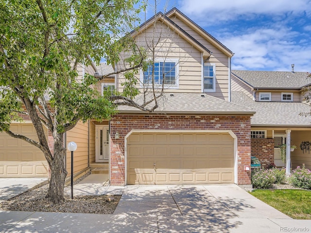 6827 S Webster St Unit E, Littleton, CO 80128 - view of front of home with brick siding, driveway, an attached garage, and a shingled roof