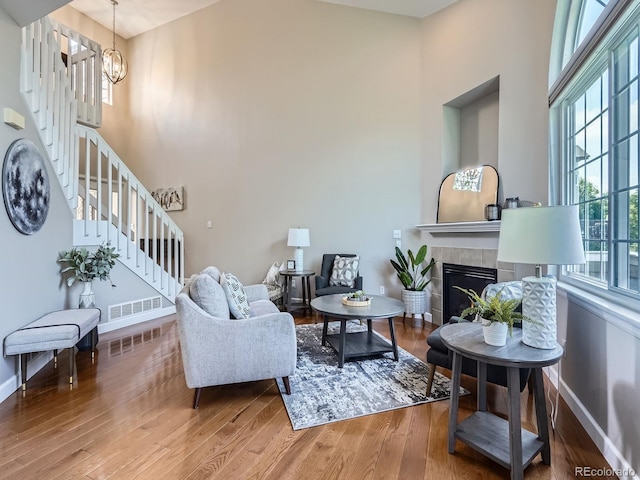 6827 S Webster St Unit E, Littleton, CO 80128 - living room featuring stairs, wood finished floors, a high ceiling, a chandelier, and a tile fireplace