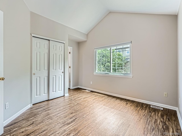 6827 S Webster St Unit E, Littleton, CO 80128 - unfurnished bedroom featuring wood finished floors, a closet, and lofted ceiling