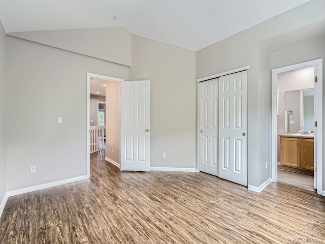6827 S Webster St Unit E, Littleton, CO 80128 - unfurnished bedroom with wood finished floors, vaulted ceiling, a closet, and ensuite bathroom