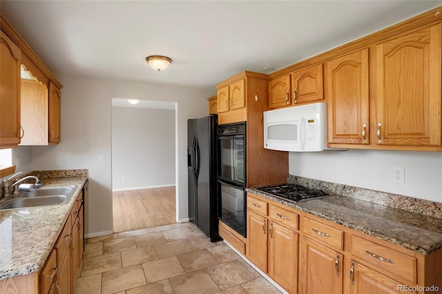 6698 S Wellington Ct, Centennial, CO 80121 - kitchen featuring a sink, black appliances, baseboards, stone countertops, and brown cabinetry