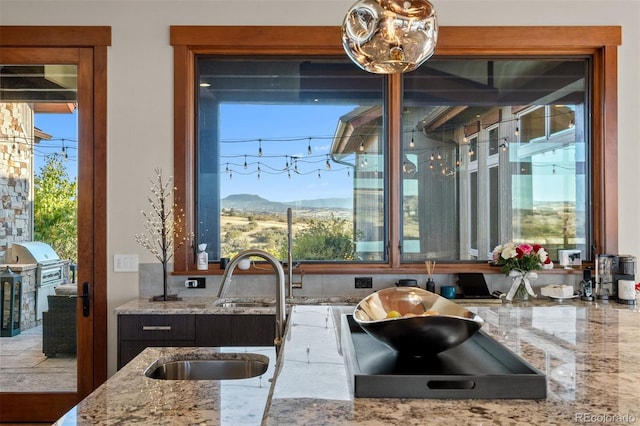 kitchen with a mountain view, light stone counters, a healthy amount of sunlight, and sink