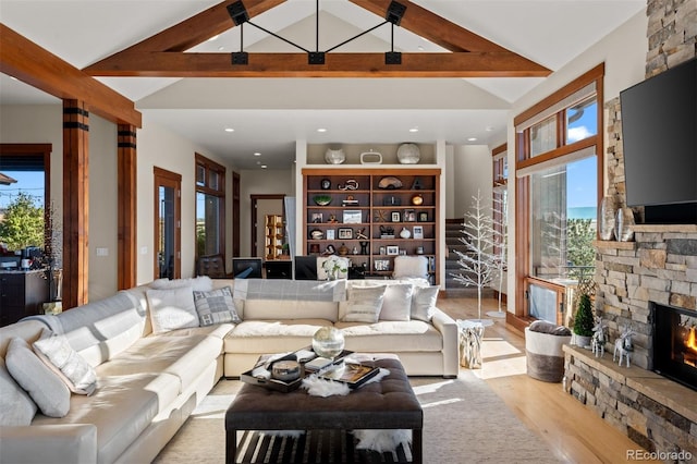 living room with light hardwood / wood-style flooring, a wealth of natural light, high vaulted ceiling, and a fireplace