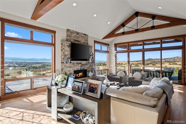 living room featuring beamed ceiling, a fireplace, light hardwood / wood-style floors, and high vaulted ceiling