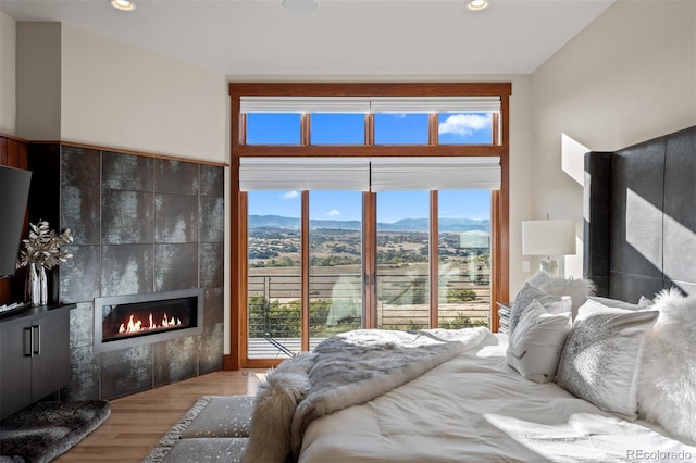 bedroom featuring wood-type flooring, a mountain view, a fireplace, and multiple windows