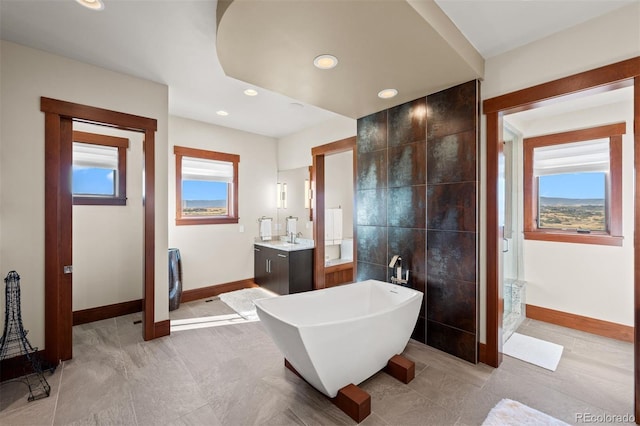 bathroom with a tub to relax in, tile walls, and vanity