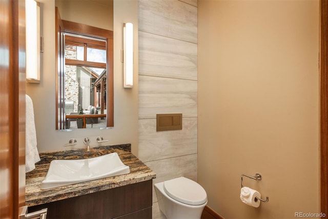 bathroom with tile walls, vanity, and toilet