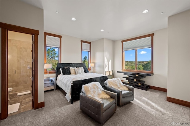 bedroom featuring carpet floors, ensuite bath, and multiple windows