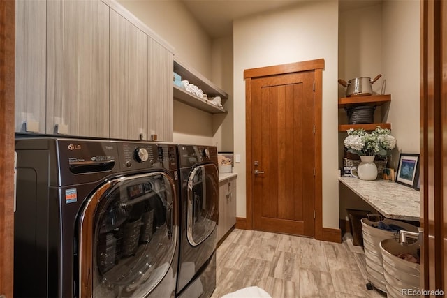 laundry room featuring separate washer and dryer, cabinets, and light wood-type flooring