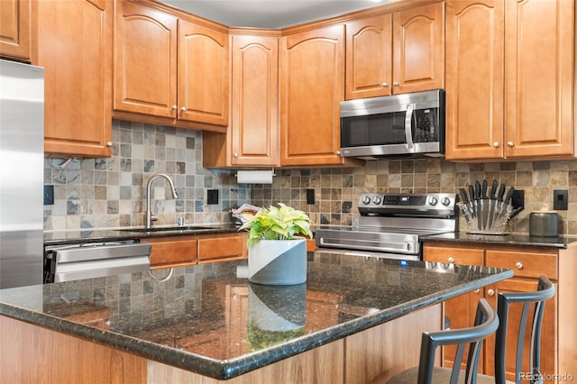 1950 N Logan St Unit 905, Denver, CO 80203 - kitchen with stainless steel appliances, a sink, backsplash, a center island, and dark stone counters