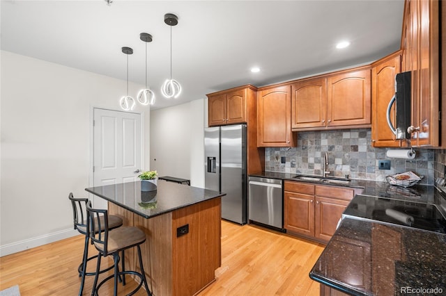 1950 N Logan St Unit 905, Denver, CO 80203 - kitchen with appliances with stainless steel finishes, a sink, light wood-style flooring, tasteful backsplash, and a kitchen island