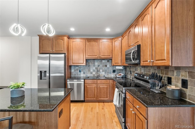 1950 N Logan St Unit 905, Denver, CO 80203 - kitchen with stainless steel appliances, a sink, light wood-style flooring, brown cabinets, and dark stone countertops