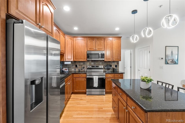 1950 N Logan St Unit 905, Denver, CO 80203 - kitchen with appliances with stainless steel finishes, light wood-style floors, brown cabinetry, tasteful backsplash, and recessed lighting