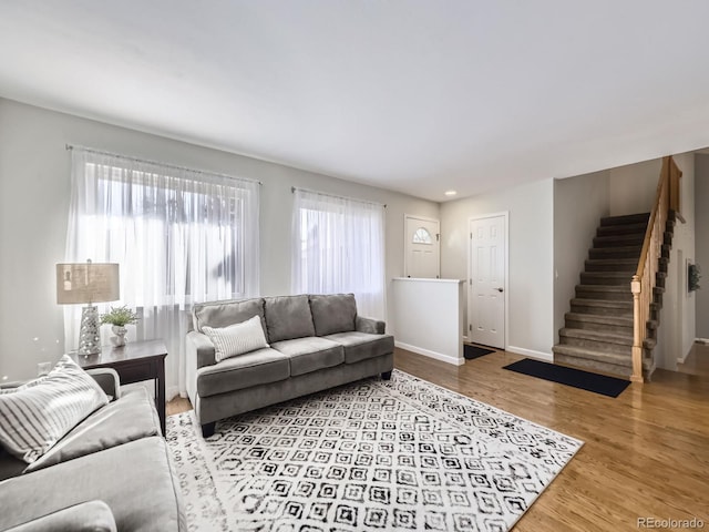 living room featuring baseboards, plenty of natural light, stairway, and wood finished floors