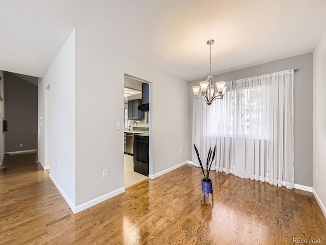 unfurnished dining area with light wood-style floors, a notable chandelier, and baseboards