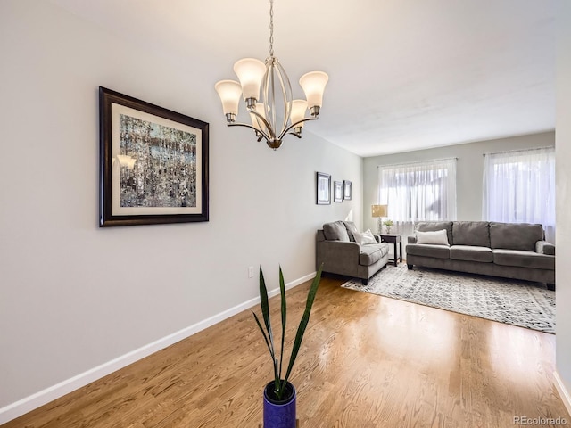 living area with an inviting chandelier, baseboards, and wood finished floors