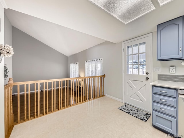 doorway to outside with vaulted ceiling and baseboards