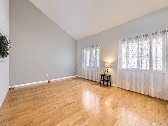 unfurnished room featuring baseboards, high vaulted ceiling, and light wood-style floors