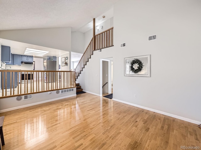 living area with light wood-style floors, stairs, and visible vents