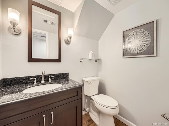 half bath featuring toilet, wood finished floors, vanity, visible vents, and baseboards