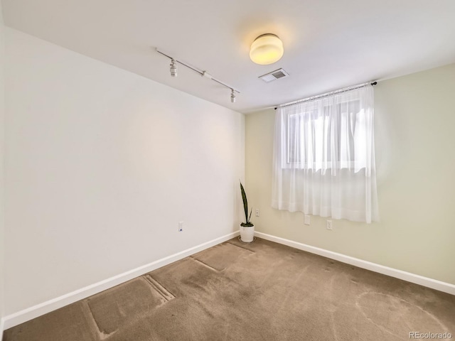 unfurnished room with carpet, baseboards, visible vents, and track lighting