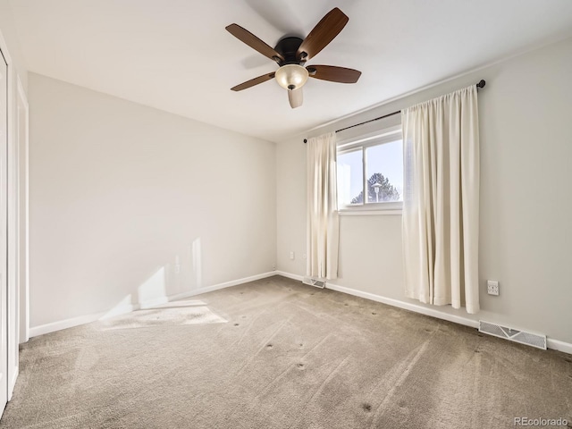 empty room featuring a ceiling fan, carpet, visible vents, and baseboards