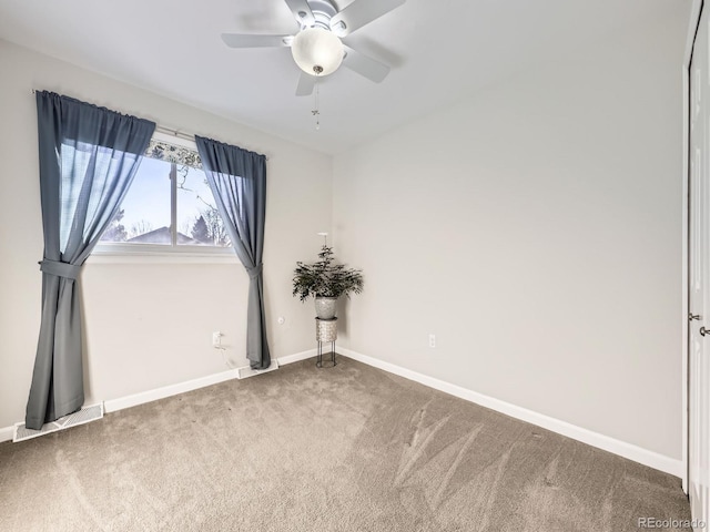 empty room with carpet floors, visible vents, baseboards, and a ceiling fan