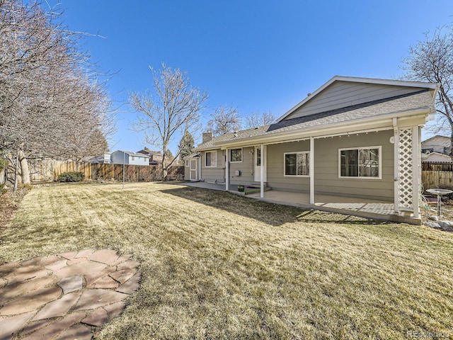 back of property featuring a chimney, a patio area, a yard, and a fenced backyard