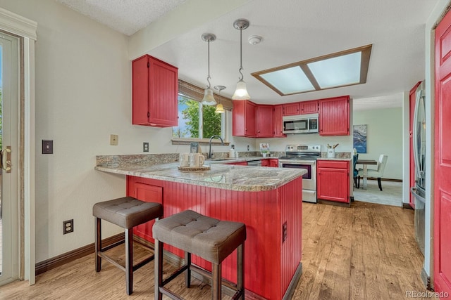 302 Northridge Rd, Highlands Ranch, CO 80126 - kitchen with appliances with stainless steel finishes, a sink, a peninsula, light wood finished floors, and decorative light fixtures