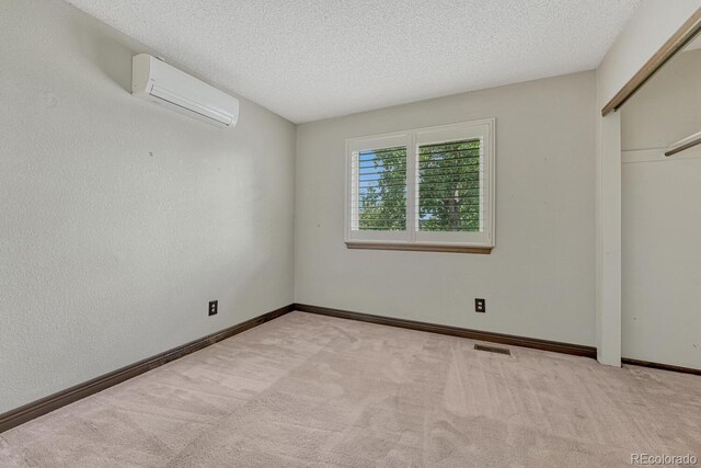 302 Northridge Rd, Highlands Ranch, CO 80126 - unfurnished bedroom featuring a wall unit AC, carpet floors, a textured ceiling, baseboards, and a closet