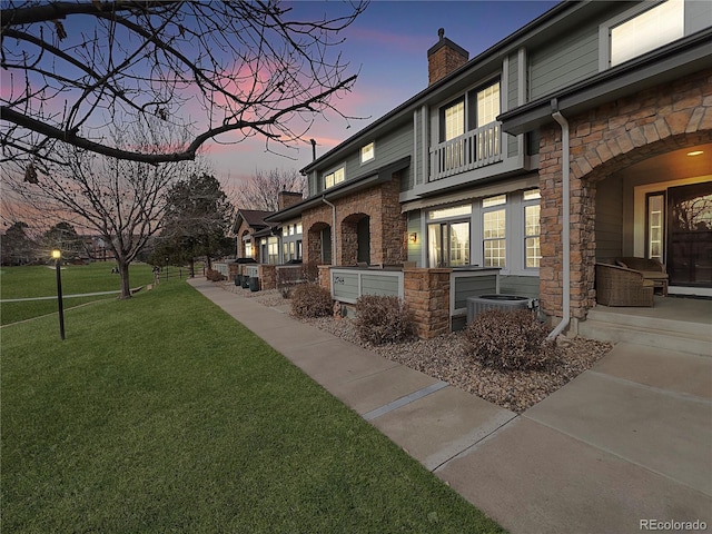 property exterior at dusk featuring a yard and central AC unit