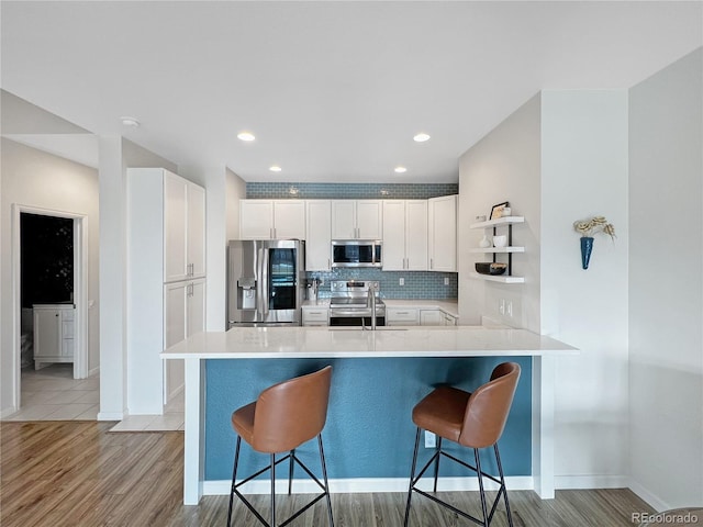 kitchen with white cabinetry, stainless steel appliances, kitchen peninsula, and a breakfast bar area