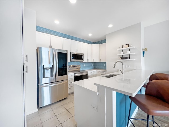 kitchen featuring sink, a breakfast bar, white cabinetry, stainless steel appliances, and kitchen peninsula