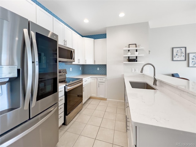 kitchen featuring appliances with stainless steel finishes, white cabinetry, sink, decorative backsplash, and light stone counters