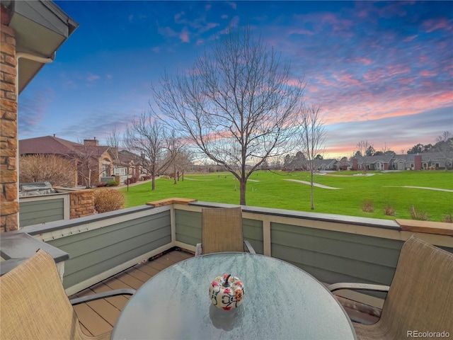 balcony at dusk featuring outdoor dining area and a residential view