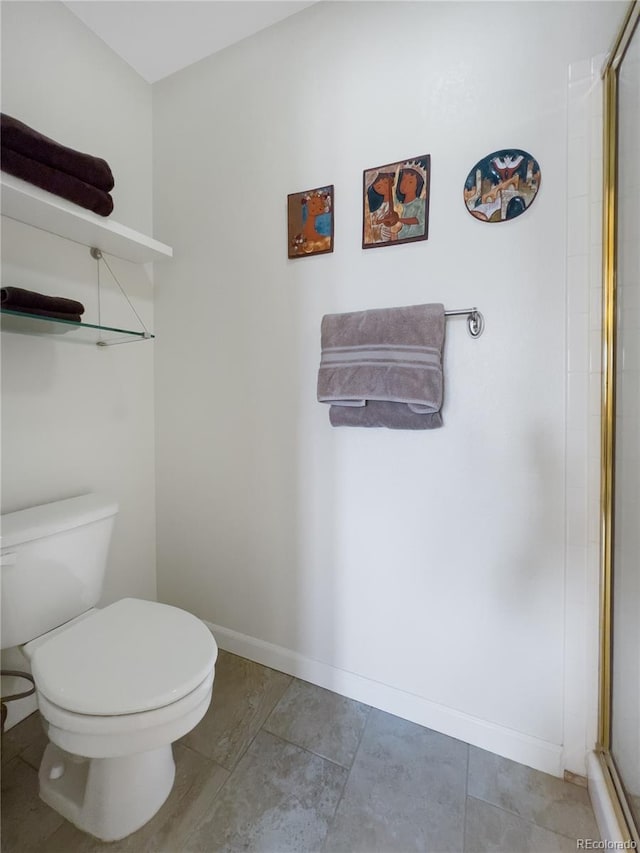 bathroom with baseboards, a shower with door, and toilet