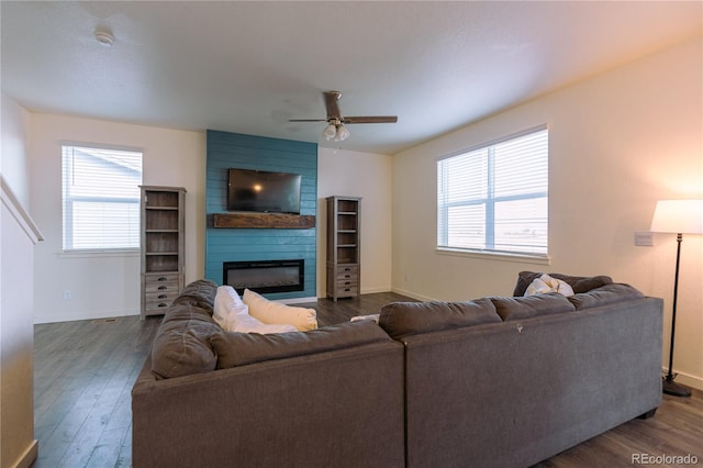 living room featuring a wealth of natural light, a large fireplace, ceiling fan, and wood-type flooring