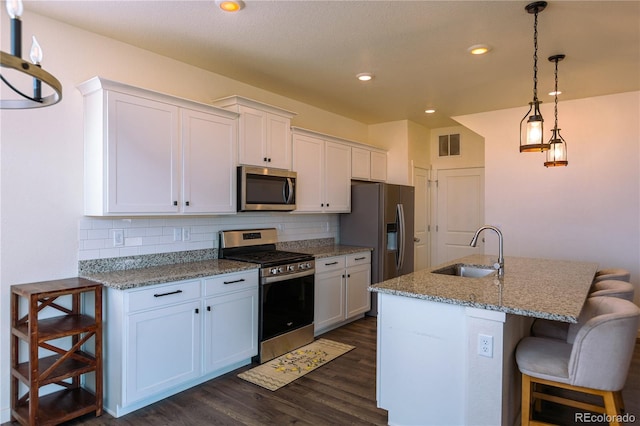 kitchen featuring white cabinets, stainless steel appliances, dark hardwood / wood-style flooring, sink, and a breakfast bar