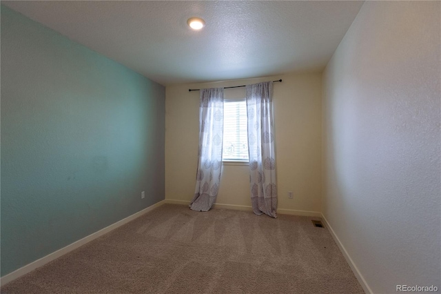 spare room featuring carpet and a textured ceiling