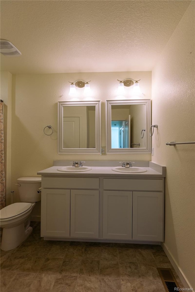 bathroom with vanity, toilet, and a textured ceiling